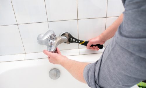 Plumber uninstalling water faucet in the bathroom